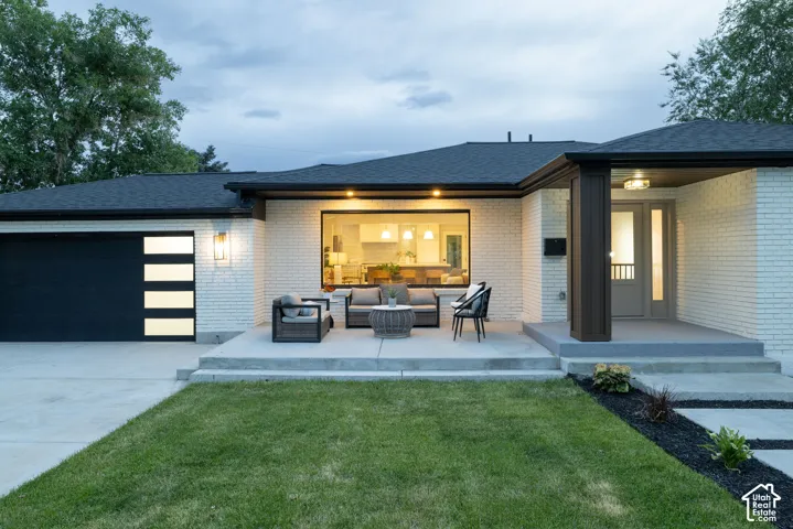White brick facade featuring a dark asphalt shingle roof and a modern garage door with translucent panels