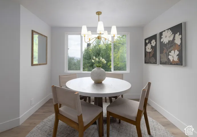 Dedicated dining area featuring wood-finish flooring, white baseboards, and a contemporary chandelier