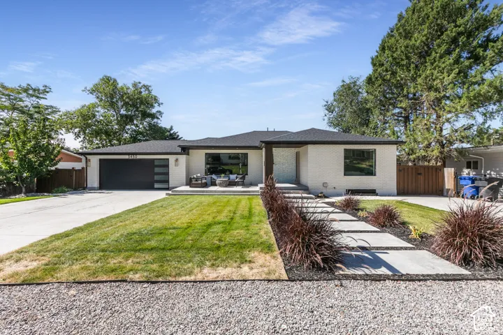 White brick exterior with a black roof, concrete driveway, and a modern garage door