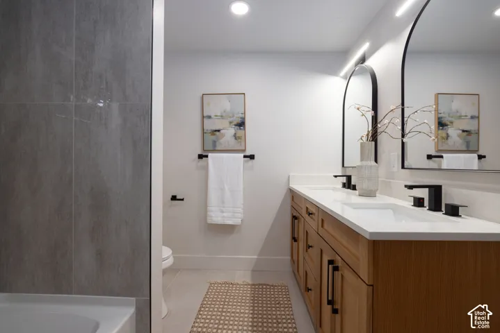 Dual vanity with wood-finish cabinetry, white countertops, and matte black fixtures