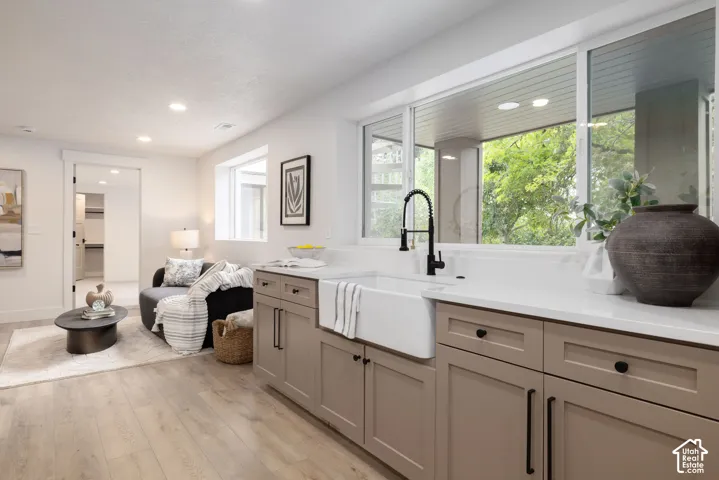 Kitchenette featuring a white farmhouse sink, matte black faucet, and light-toned cabinetry with dark hardware