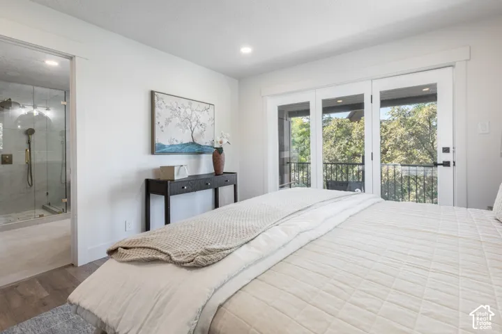 Wood-finish flooring, recessed lighting, glass-enclosed shower, French doors, and a balcony with an iron railing