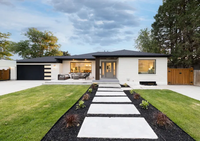Contemporary single-story residence featuring a white brick exterior and a dark roof