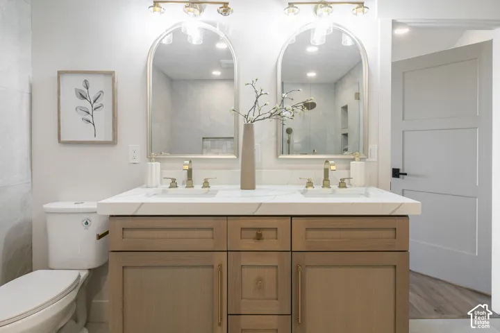 Double vanity with a white countertop and integrated sinks, illuminated by overhead sconces