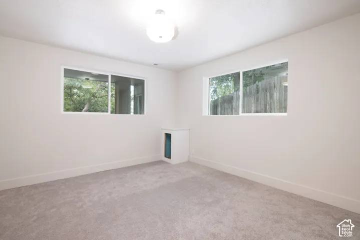Neutral tone wall paint with a textured ceiling finish, two windows, wall-to-wall carpeting, and a built-in wall niche
