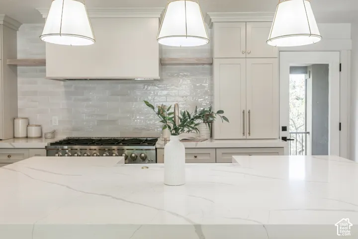 Kitchen featuring a large central island with a light-toned countertop, stainless steel range, and subway tile backsplash