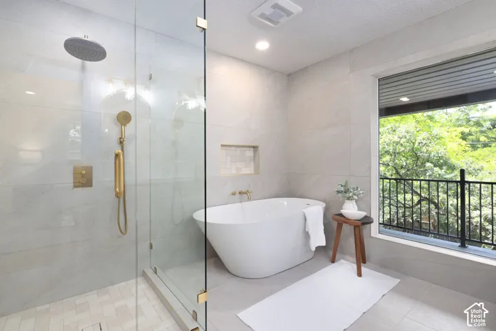 Contemporary bathroom featuring a freestanding soaking tub, a frameless glass shower enclosure with gold-tone fixtures, and a recessed tiled niche