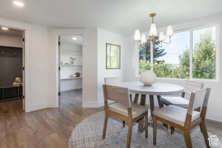 Spacious dining area with a multi-pane window, wood-finish flooring, and a brass chandelier