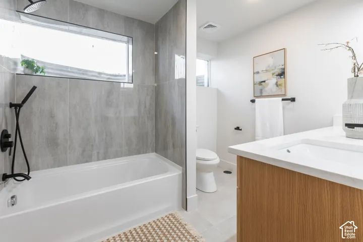 Bathroom featuring a soaking tub with matte black fixtures, an elongated window, a modern vanity with an integrated sink, and light wood-finish cabinetry
