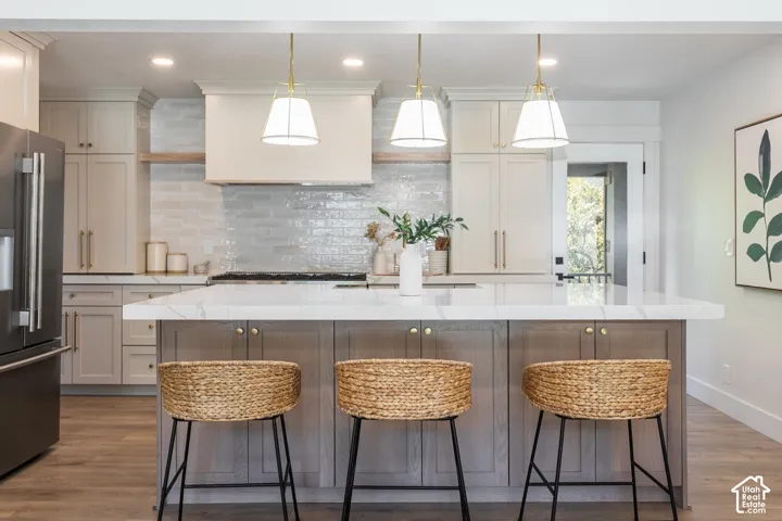 Kitchen featuring a central island with countertop, wood-finish flooring, built-in cabinetry, and pendant lighting