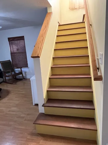 Staircase featuring wood-finish treads and handrails, complemented by light-toned risers