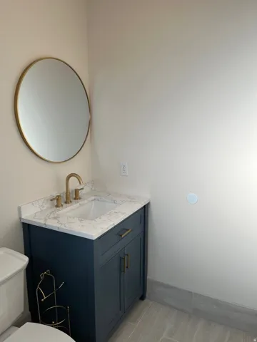 Vanity with a white countertop and integrated sink, gold-toned faucet, and dark blue cabinetry