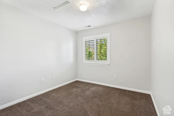 Room featuring light gray walls, brown carpet flooring, and white baseboards