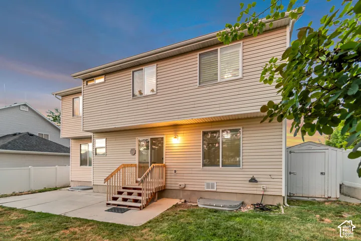 Rear exterior featuring beige horizontal siding, a ground-level concrete patio, and a multi-level wooden deck with stairs