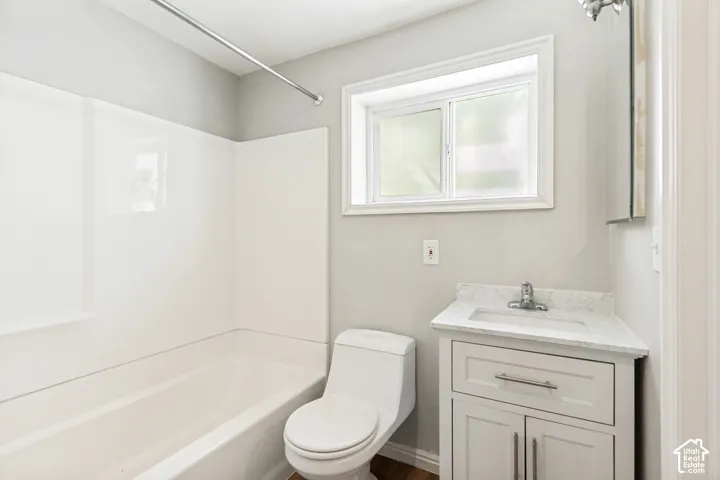 Bathroom featuring a white bathtub, toilet, and vanity with a light-colored countertop