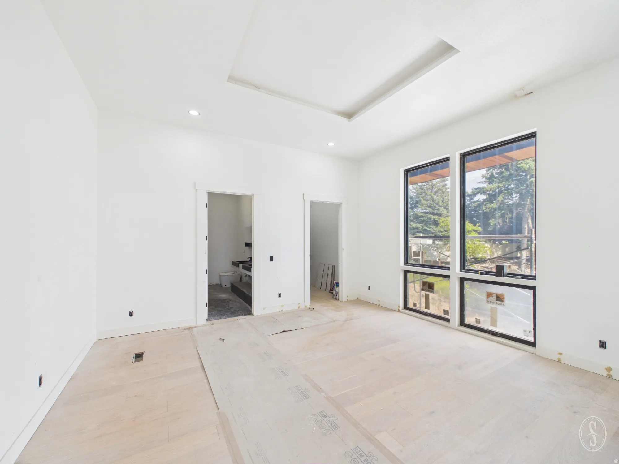 Expansive room featuring light wood-finish flooring and a tray ceiling with recessed lighting
