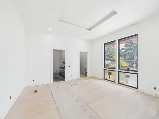 Expansive room featuring light wood-finish flooring and a tray ceiling with recessed lighting