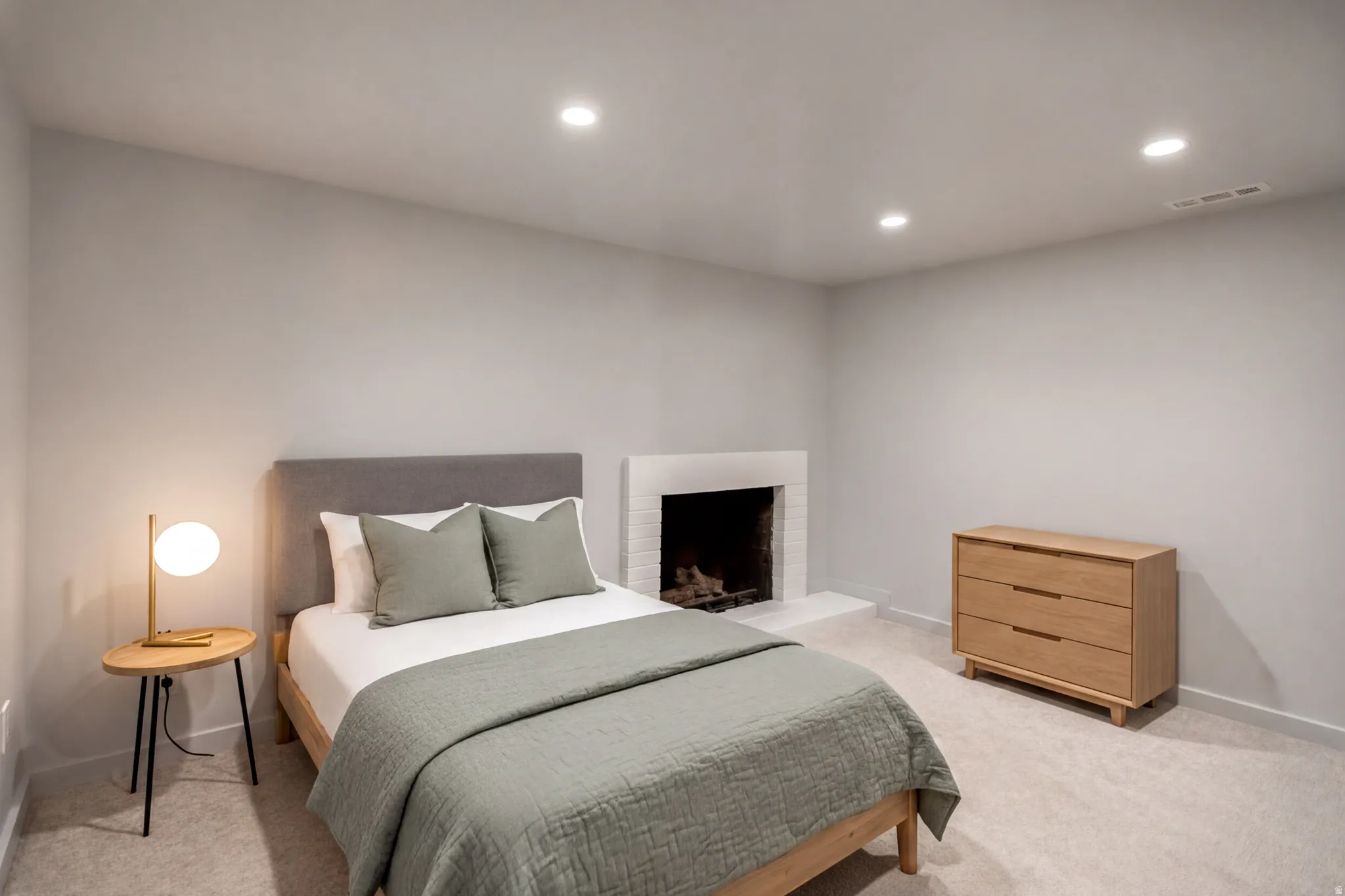 Interior room featuring a white brick fireplace with a raised hearth, light gray carpeting, and recessed lighting. Virtually staged