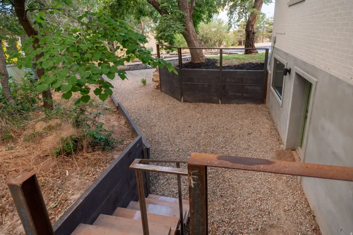 Outdoor gravel area bordered by a concrete wall with a window and door