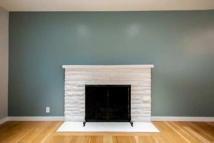 Fireplace featuring a white stacked stone surround, a black metal screen, and a white hearth