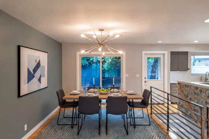Dining area featuring a contemporary chandelier, wood-finish flooring, and a sliding glass door. Virtually staged