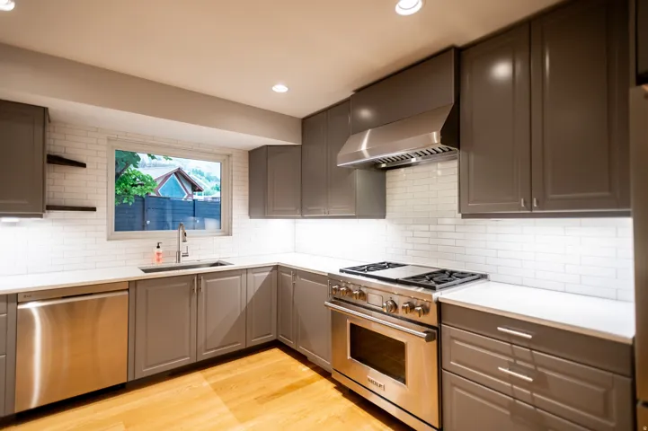 Contemporary kitchen featuring gray cabinetry, stainless steel appliances, white subway tile backsplash, recessed lighting, and wood-finish flooring