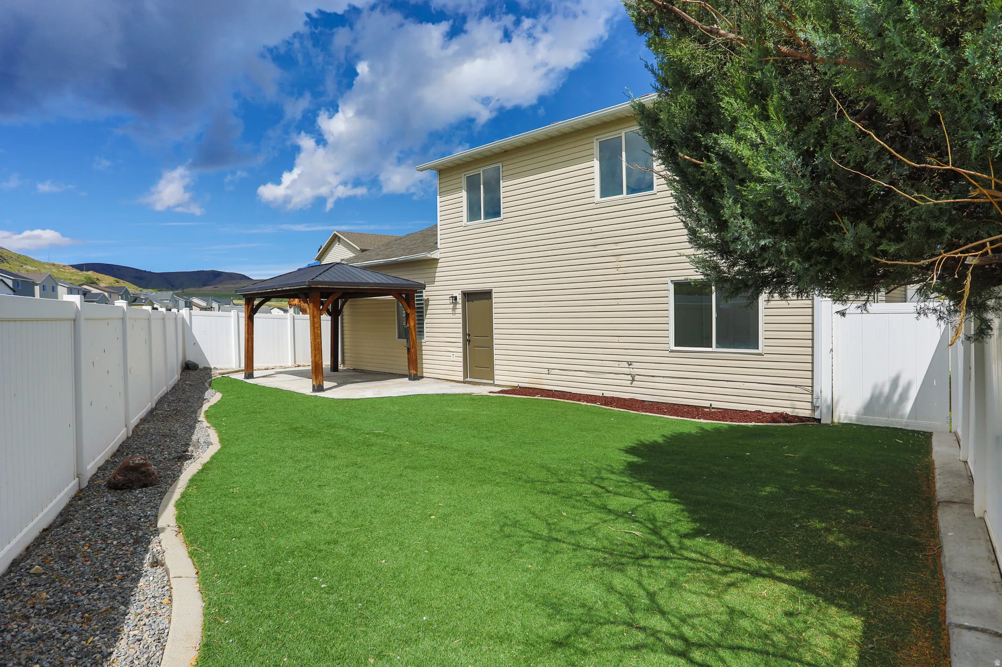 Backyard featuring a covered patio structure, artificial turf lawn, and perimeter fencing