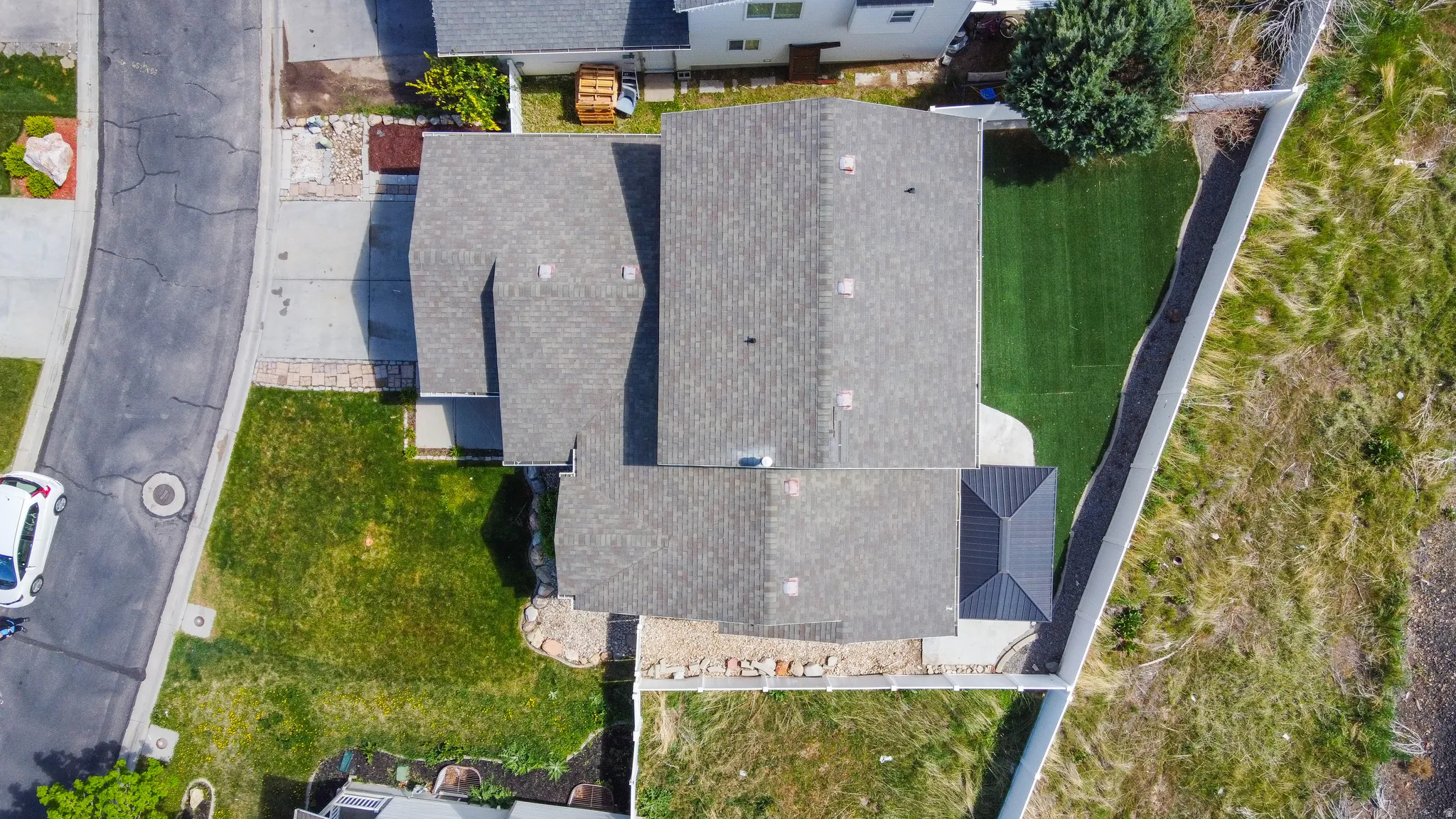 Aerial view showcasing a residential property with a shingle roof and a paved driveway