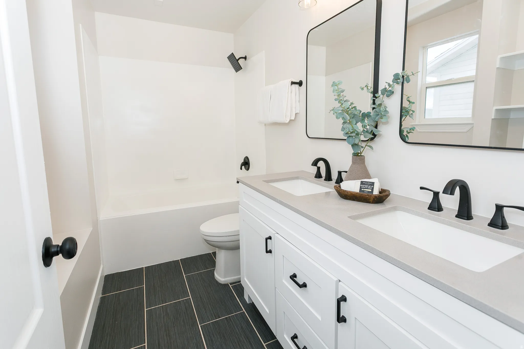 Bathroom featuring a dual vanity with light-toned countertops, integrated sinks, and matte black fixtures