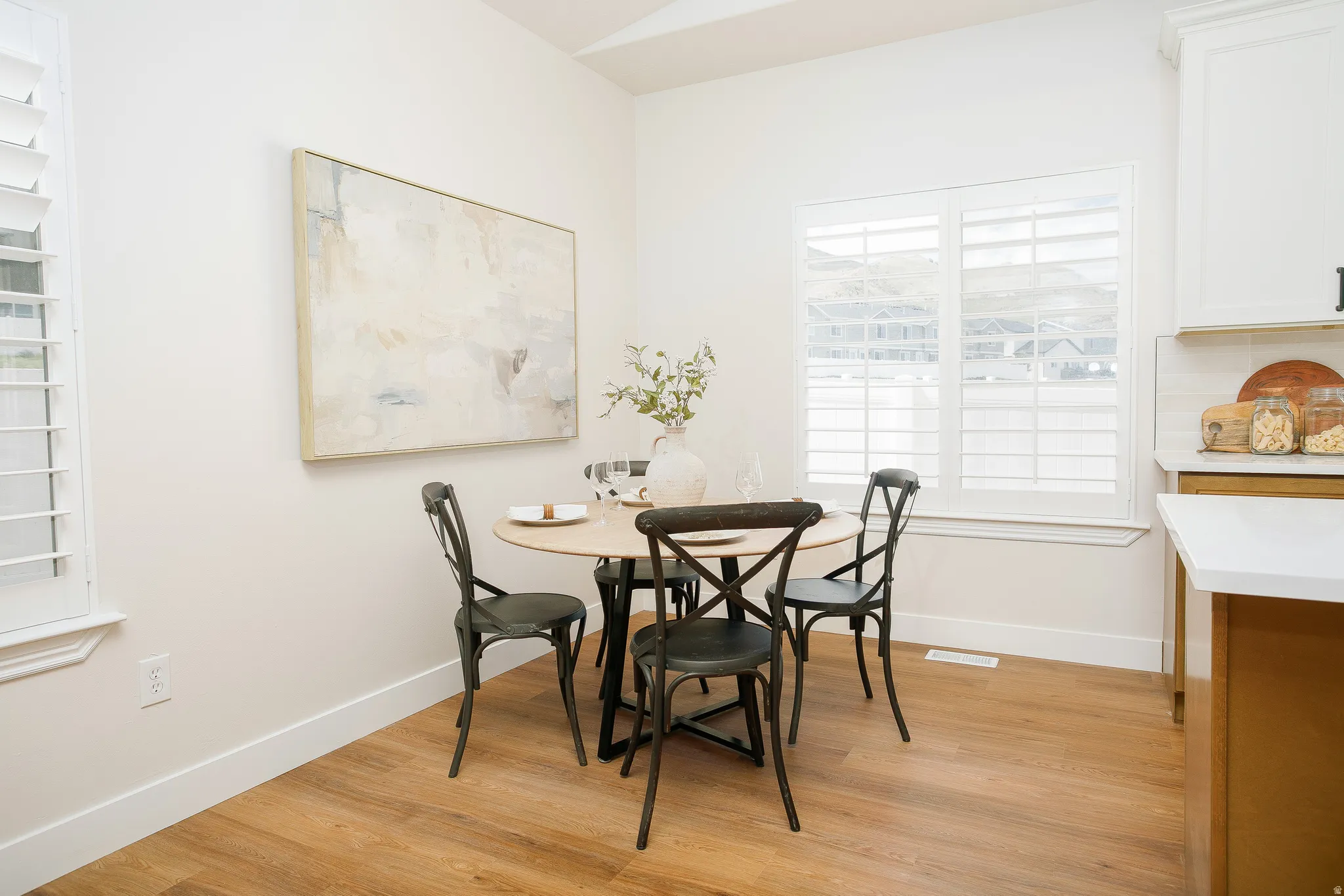 Breakfast nook featuring wood-finish flooring, white plantation shutters, vaulted ceiling, and a white countertop