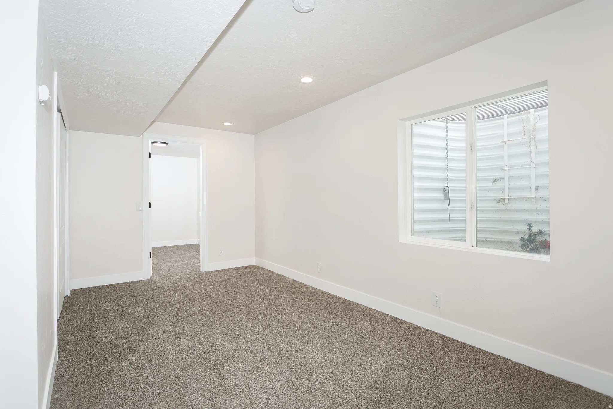 Carpeted room with recessed lighting and a white-framed window