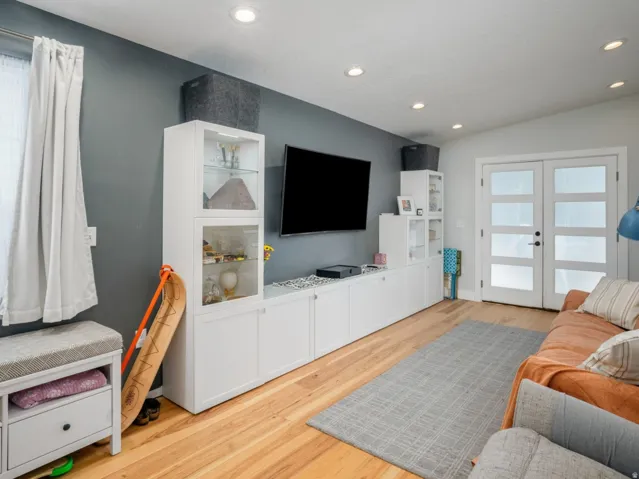 Vaulted ceiling featuring recessed lighting, wood-finish flooring, and white built-in cabinetry