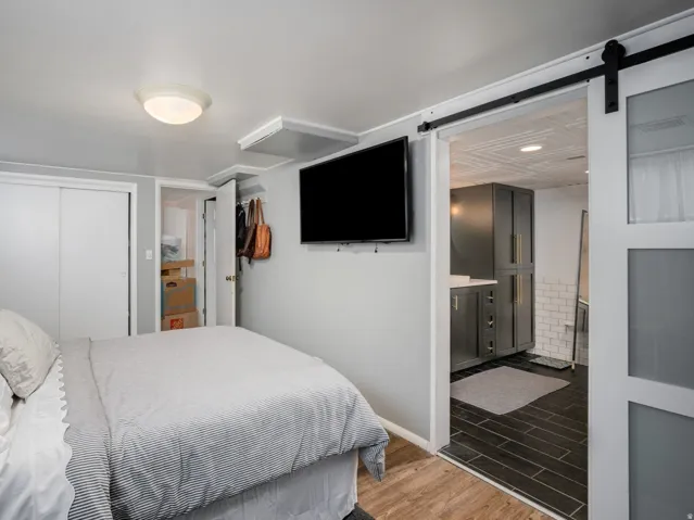 Bedroom featuring wood-finish flooring, a wood headboard, and a double sliding closet door