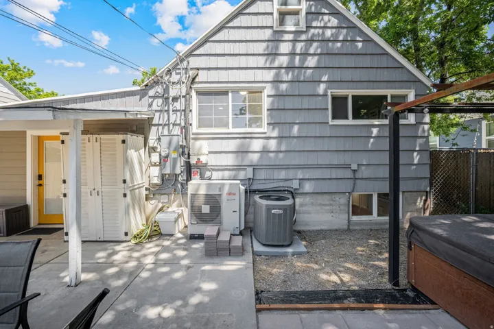 Rear facade with gray shingle siding and a yellow exterior door