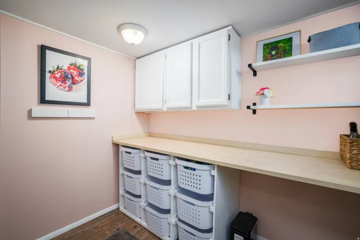 Laundry area featuring a wood-finish countertop, white upper cabinetry, and integrated storage shelving