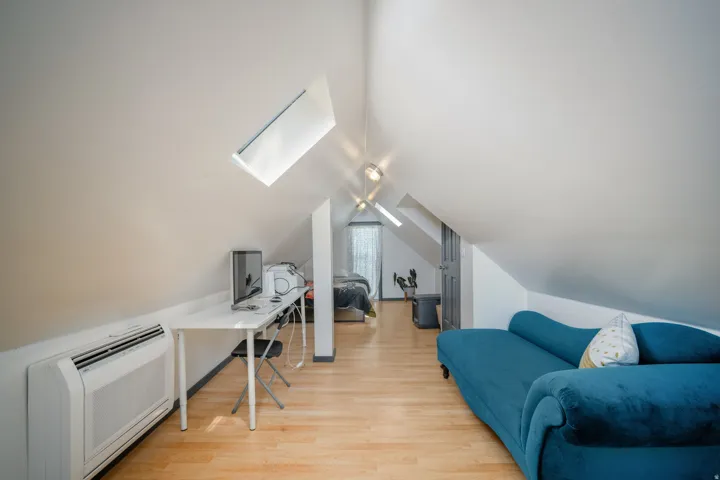 Attic space with light wood-finish flooring, two skylights, and sloped ceilings