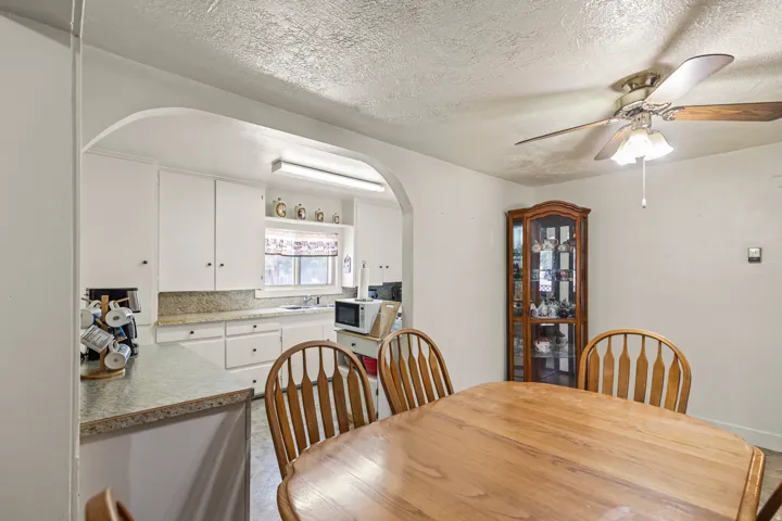 Dining area featuring a wood-finish ceiling fan, an arched entryway, and a breakfast bar with a light-toned countertop