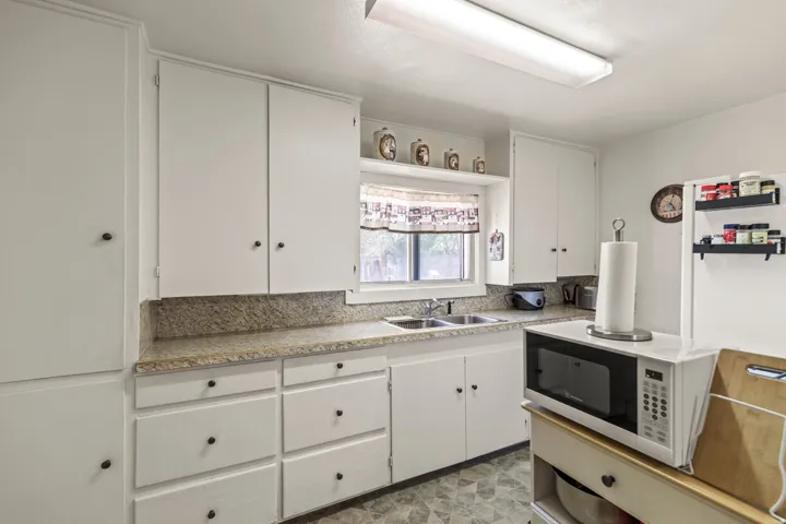 Kitchen featuring white cabinetry, granite-style countertops, and a double-basin stainless steel sink