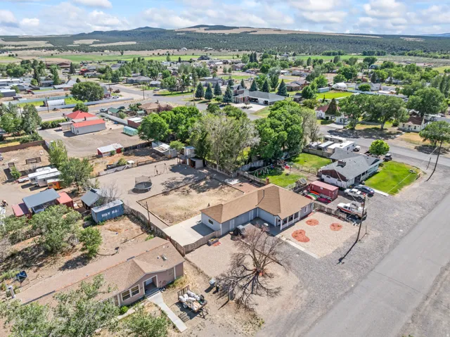 Aerial perspective showcasing the primary residence with a light brown shingle roof and covered porch