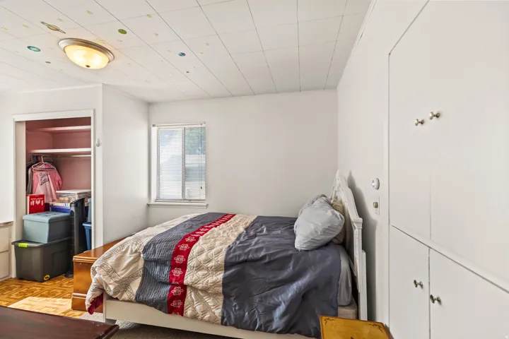 Bright room featuring a single window, built-in closet with shelving, and a panel ceiling with a flush-mount light fixture