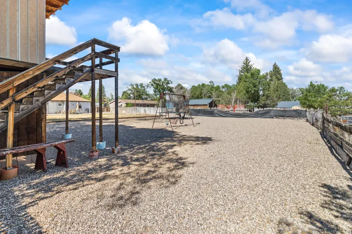 Expansive gravel-covered outdoor area featuring a wooden staircase and a rustic wooden fence line