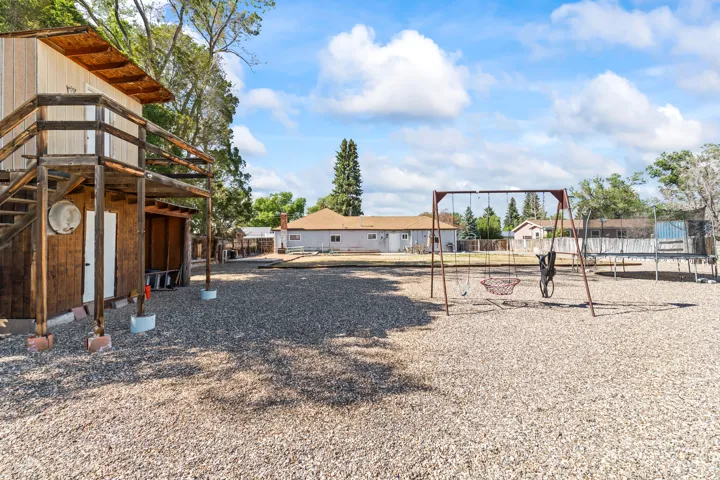 Expansive gravel yard featuring a multi-level outbuilding with wood siding and a covered porch