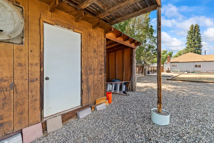 Wood-sided outbuilding with an attached lean-to structure and white entry door