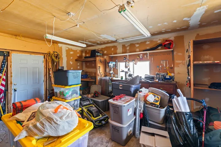Interior garage space featuring a work bench, wall-mounted shelving, built-in storage, a window, and fluorescent lighting