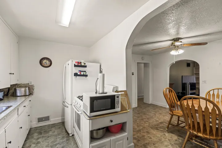 Kitchen featuring white cabinetry, stone-finish countertops, and a white refrigerator