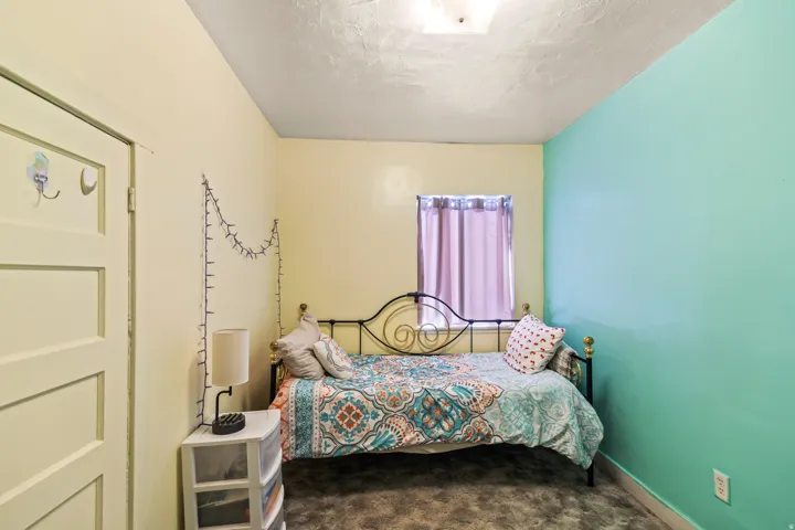 Bedroom featuring two-tone wall paint, a window with curtains, and textured ceiling
