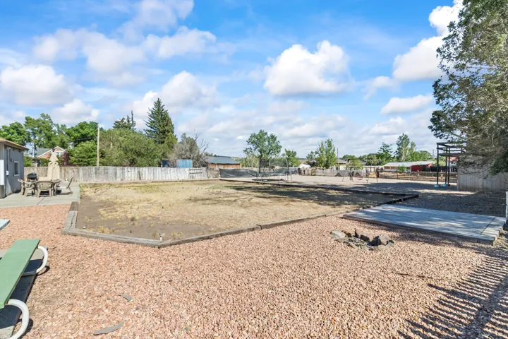 Expansive outdoor space featuring a large central area, a gravel-covered surface, a concrete patio, and a privacy fence