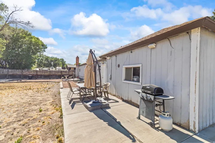 Concrete patio extending along the side of the structure, featuring vertical siding and a single window