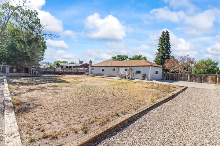 Expansive exterior lot featuring a gravel driveway, a wooden fence, and mature trees