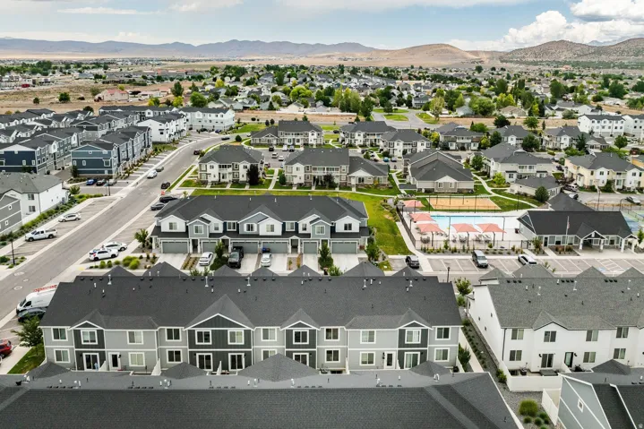 Aerial view of a residential community featuring rows of townhomes and single-family residences